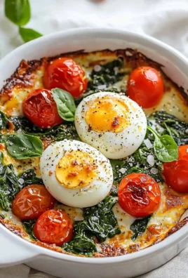 Baked feta eggs with tomatoes and spinach served in a dish