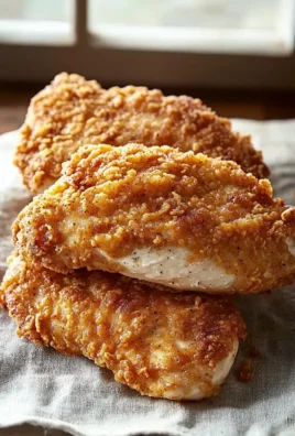 Plate of crispy Chicken-Fried Chicken Breasts served with gravy and sides