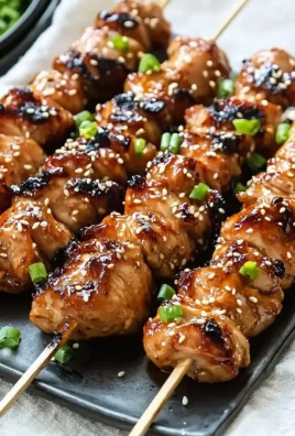 Grilled teriyaki chicken skewers served on a plate with garnish.
