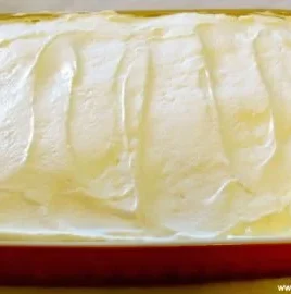 Delicious banana pudding poke cake slice topped with whipped cream and bananas
