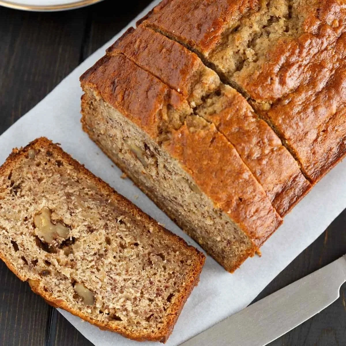 Loaf of best ever banana bread on a wooden table with slices cut
