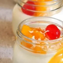 Coconut Mango Panna Cotta dessert garnished with mango slices and coconut flakes.