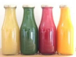 Four colorful kid-friendly juice recipes in glasses with fruits and vegetables