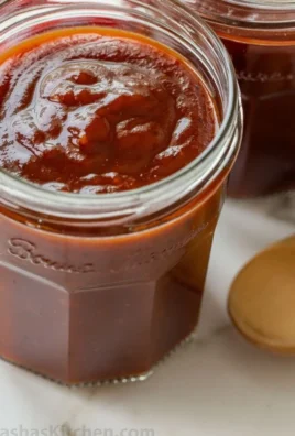 Homemade BBQ sauce in a jar with fresh ingredients displayed around it.