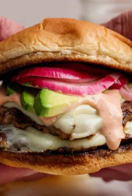 Juicy turkey smash burger with burger sauce and pickled onions on a plate.