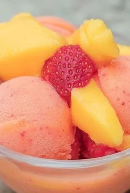 Delicious mango strawberry sorbet in a bowl garnished with fresh fruit.