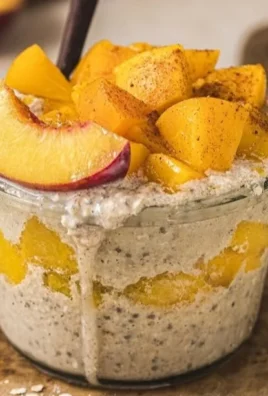 Bowl of peach cobbler overnight oats with fresh peaches and granola