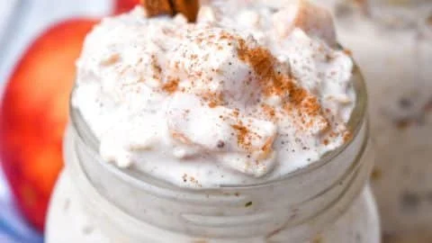 Peaches and cream overnight oats in a jar with fresh peach slices on top