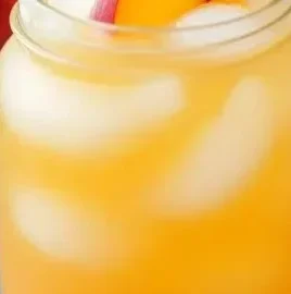 Refreshing peach lemonade served in a glass with fresh peaches and lemons
