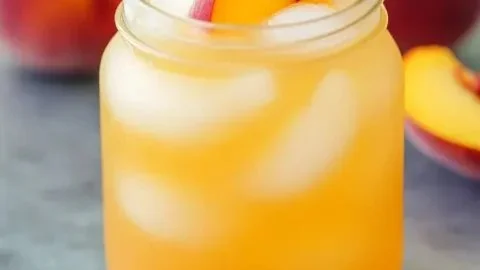 Refreshing peach lemonade served in a glass with fresh peaches and lemons