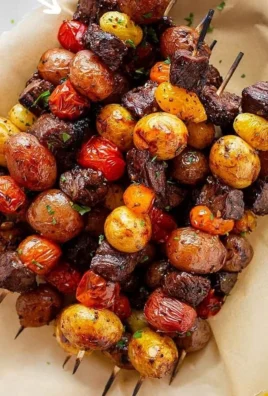 Rosemary garlic steak kebabs ready for grilling, showcasing tender beef chunks and herbs.