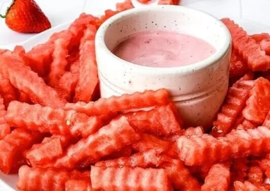 TikTok watermelon fries served with strawberry yogurt dip in a vibrant bowl.