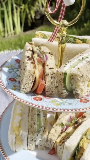 A platter of delicious vegetarian afternoon tea sandwiches with fresh vegetables and spreads.