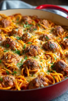 Baked spaghetti and meatballs served in a dish, garnished with parsley