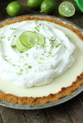 Delicious slice of best key lime pie topped with whipped cream and lime zest