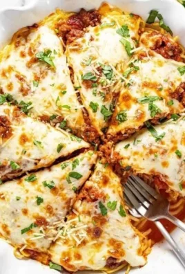 Delicious cheesy spaghetti pie served on a plate with herbs