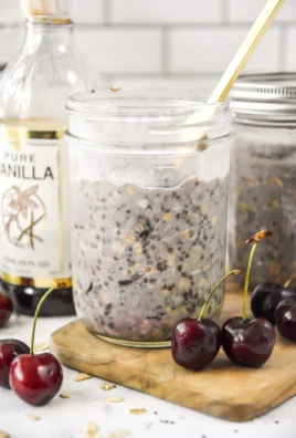 Delicious cherry vanilla overnight oats in a glass bowl topped with fresh cherries.