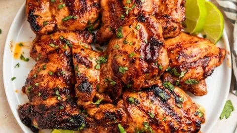 Chili Lime Grilled Chicken served on a plate with fresh herbs and lime wedges