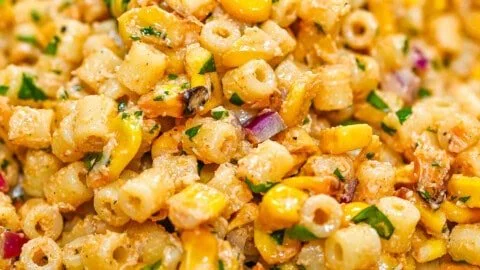 Colorful bowl of corn pasta salad with vegetables and dressing