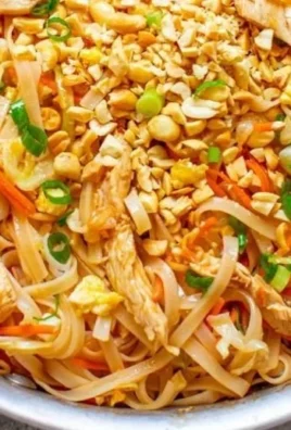 Plate of Easy Chicken Pad Thai garnished with lime and peanuts