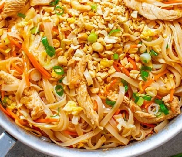 Plate of Easy Chicken Pad Thai garnished with lime and peanuts