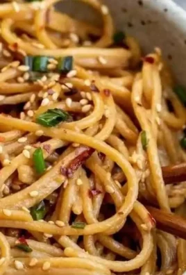 Plate of easy garlic sesame noodles garnished with sesame seeds and scallions
