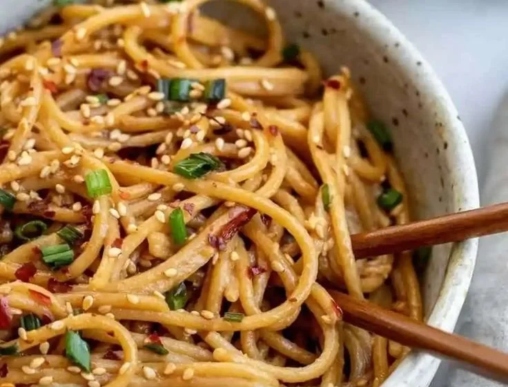 Plate of easy garlic sesame noodles garnished with sesame seeds and scallions
