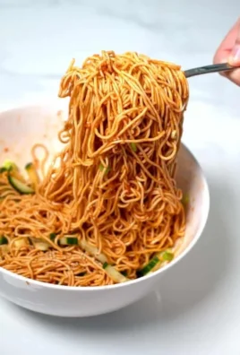 Bowl of easy Korean cold noodles garnished with vegetables and sesame seeds.