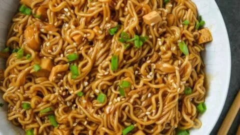 Bowl of easy saucy ramen noodles garnished with green onions and sesame seeds