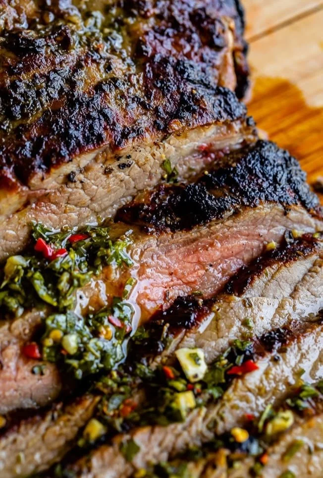 Juicy grilled flank steak served with garnishes on a plate