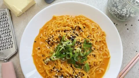 Bowl of homemade Buldak Carbonara Noodles garnished with herbs