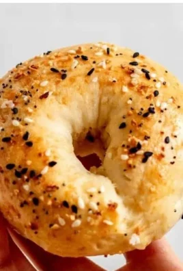 Freshly baked homemade protein bagels with toppings on a wooden board.
