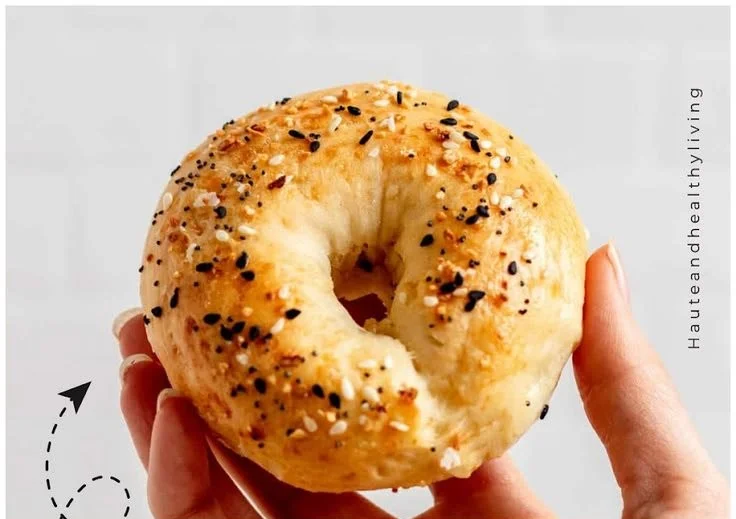 Freshly baked homemade protein bagels with toppings on a wooden board.