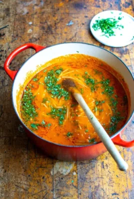 Bowl of steaming noodle soup with fresh herbs and vegetables