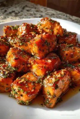 Oven roasted honey garlic salmon bites served on a plate with vegetables.