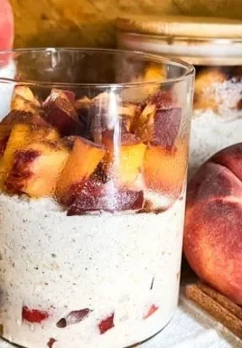 Delicious Peach Cobbler Overnight Oats in a glass bowl with fresh peaches