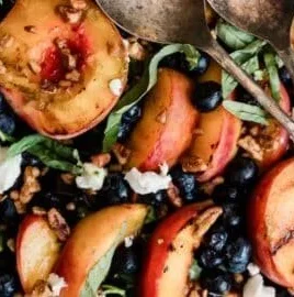 Delicious stone fruit grilled salad topped with fresh greens and drizzled with dressing.