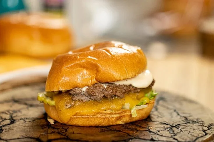 Delicious homemade smash burger on a grill with toppings