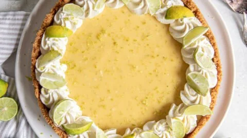 Slice of traditional key lime pie on a plate with lime slices decor