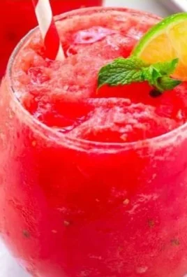 Refreshing watermelon slushie in a glass surrounded by fresh watermelon slices