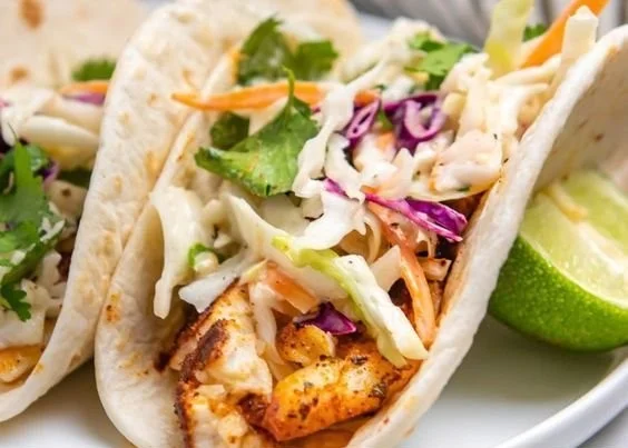 Delicious air fryer fish tacos plated with fresh toppings and lime wedges