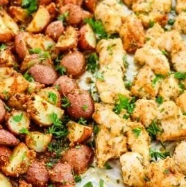 Baked garlic parmesan chicken served with roasted potatoes on a plate.