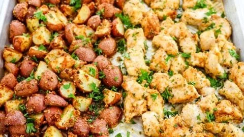 Baked garlic parmesan chicken served with roasted potatoes on a plate.