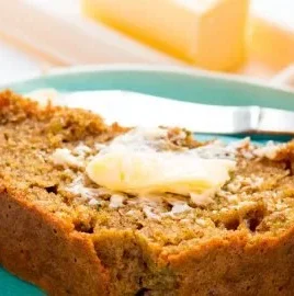 Moist orange zucchini bread with slices on a wooden table
