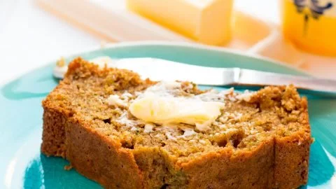 Moist orange zucchini bread with slices on a wooden table
