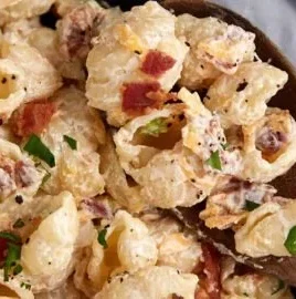 Bacon cheddar ranch pasta salad served in a bowl, garnished with fresh herbs.