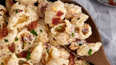Bacon cheddar ranch pasta salad served in a bowl, garnished with fresh herbs.
