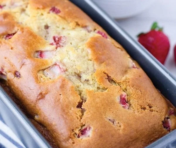 Slices of fresh strawberry quick bread with strawberries on the side