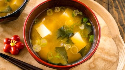 Bowl of homemade miso soup with tofu and green onions served with chopsticks.