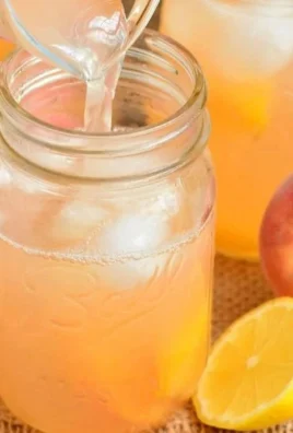 Refreshing homemade peach lemonade in a glass with fresh peaches and lemons